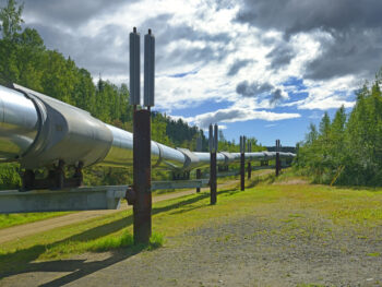 Large silver pipeline elevated above ground with blue sky & clouds in background. on of the best things to do in Fairbanks Alaska