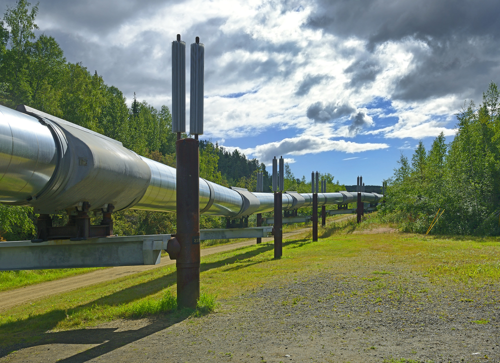 Large silver pipeline elevated above ground with blue sky & clouds in background. on of the best things to do in Fairbanks Alaska