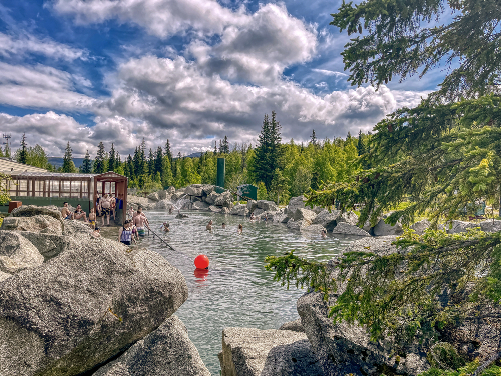 People relaxing in the Chena Hot Springs. The spring is surrounded by foilage.