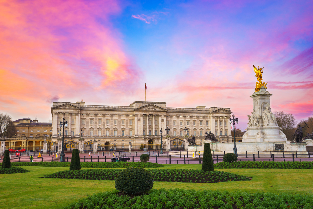 Buckingham Palace at sunrise. The picture is taken from the Mall and you can see greenary and the statue in the foreground. 