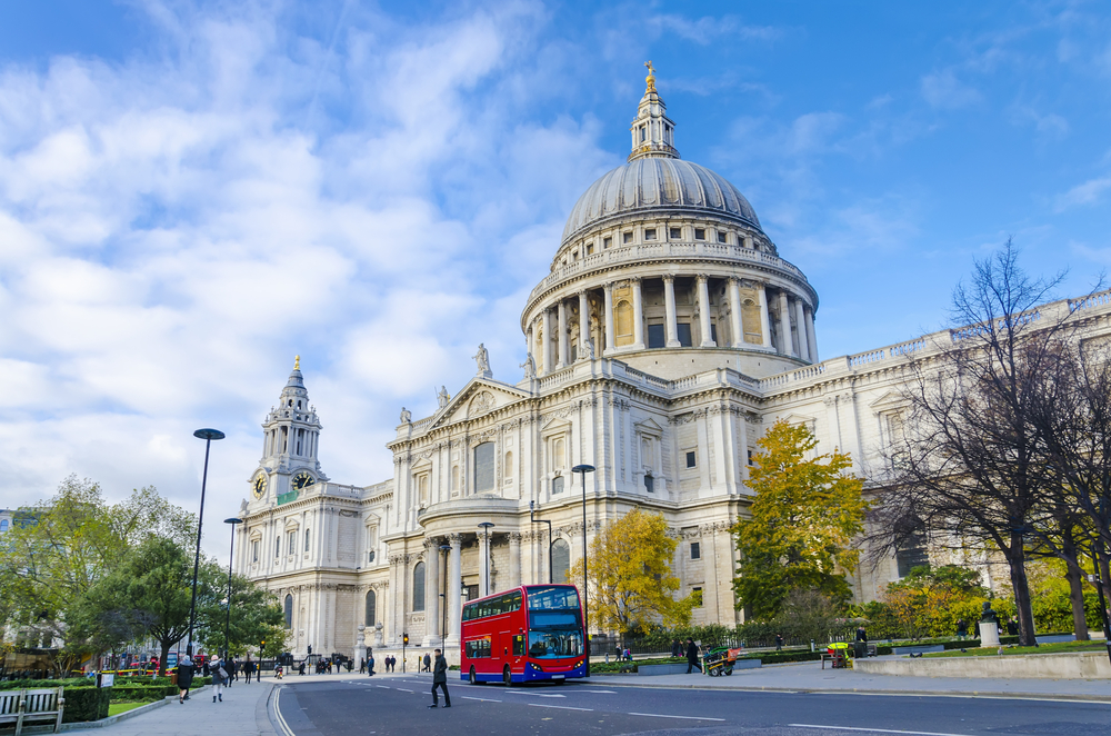 St. Pauls cathedral with red double decker bus on the street outside in an article about tours in London. 