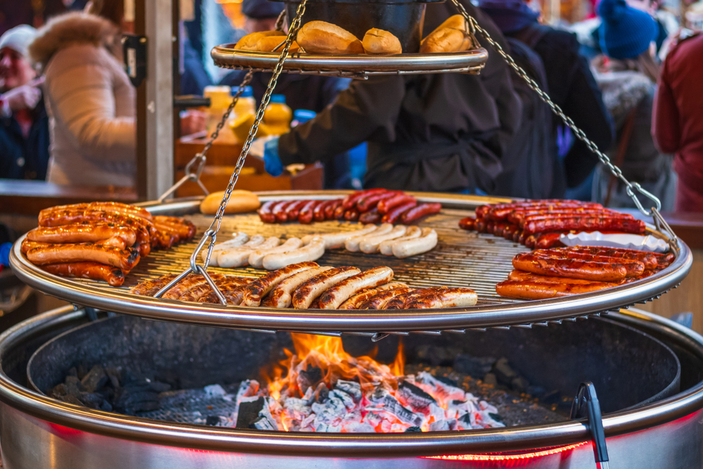Grilling sausages on barbecue grill at a food stall of Christmas market. 
