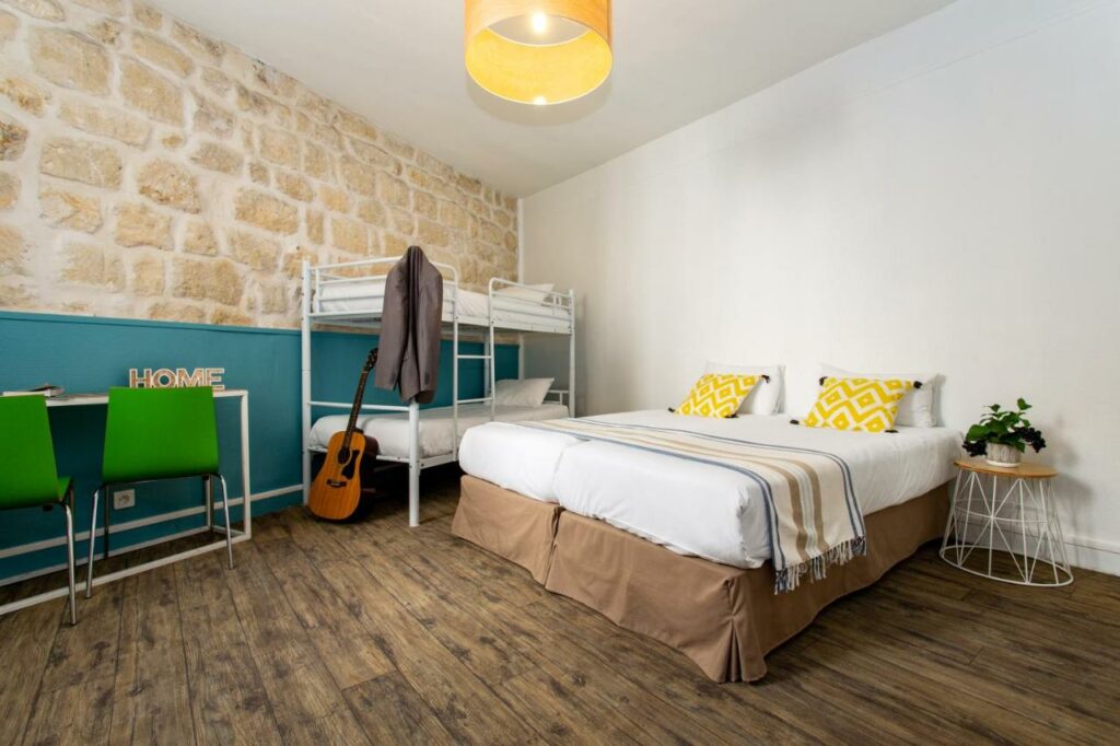 Room with a double bed and bunk bed at Le Regent Montmartre, one of the best hostels in Paris.