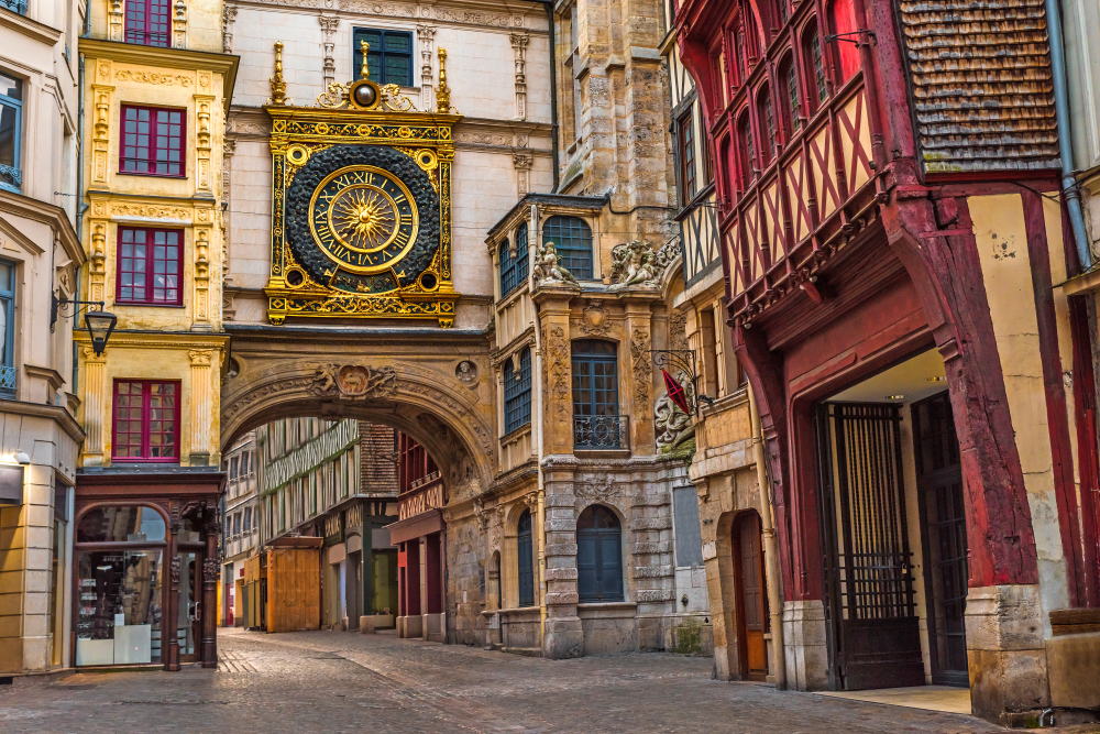 The golden astronomical clock over a cute, historic street in Rouen, one of the best day trips from Paris by train.