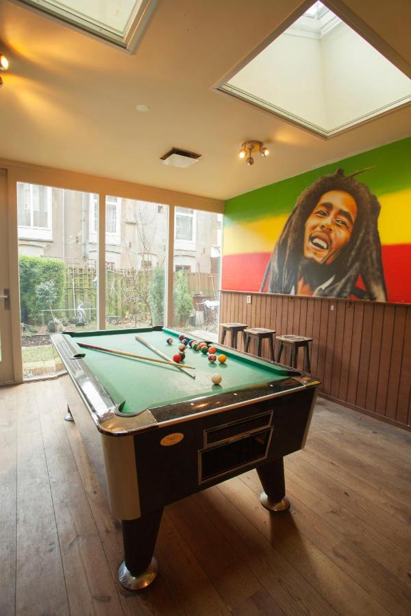 A pool table under a painting of Bob Marley at The Flying Pig Uptown hostel.