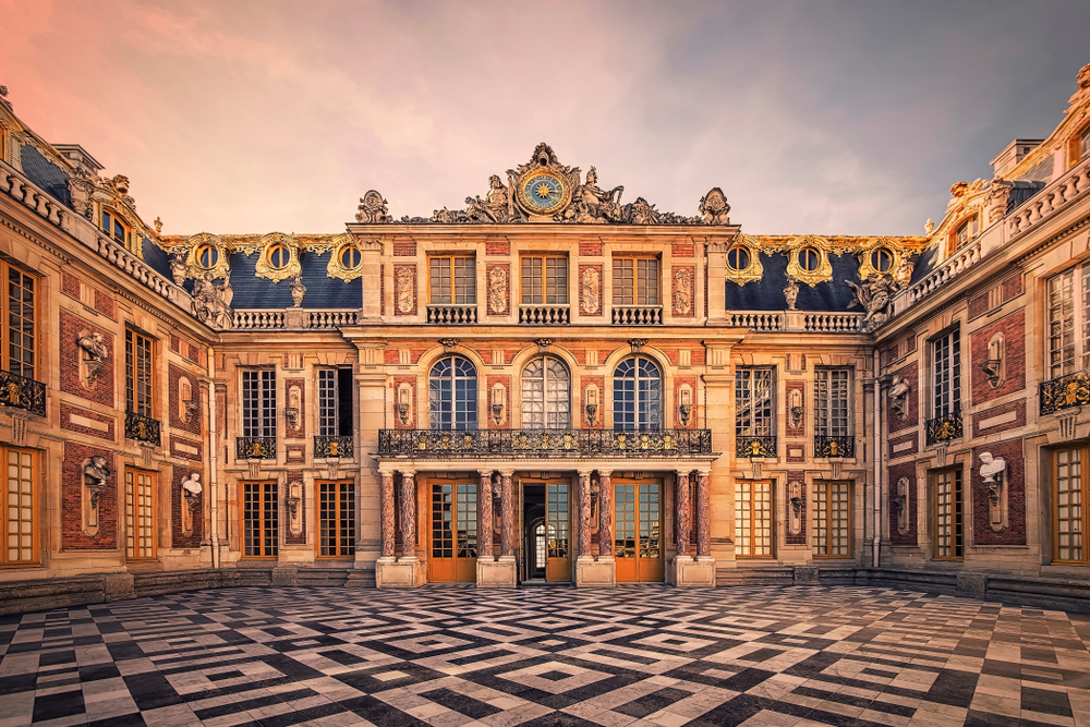 Sunset over the entrance to the Château de Versailles with marble tiles.