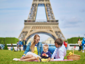 Family picnicking under the Eiffel Tower while visiting Paris with kids.