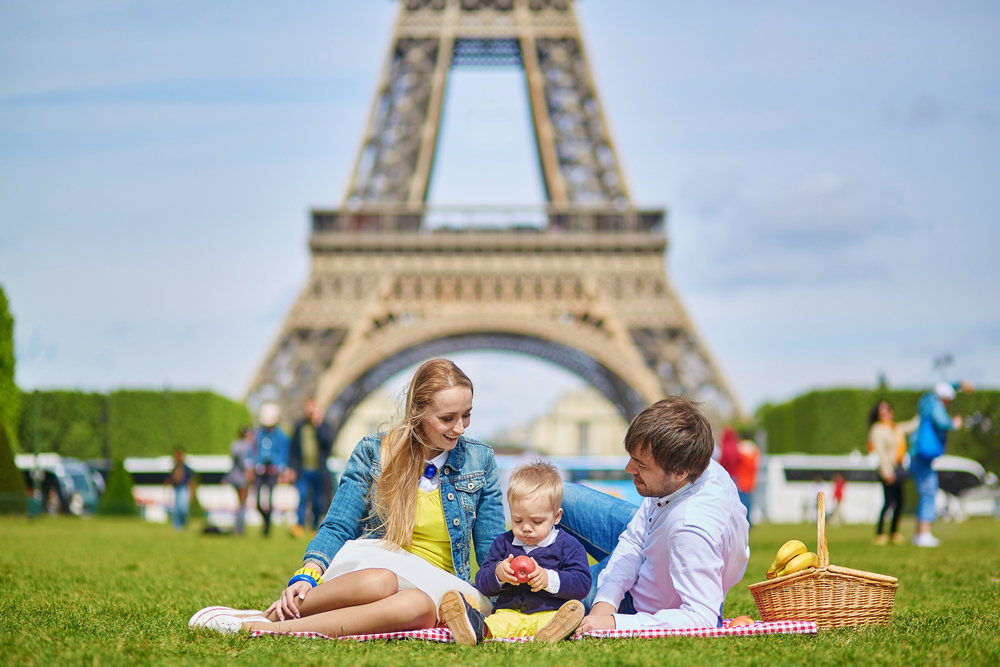 Family picnicking under the Eiffel Tower while visiting Paris with kids.