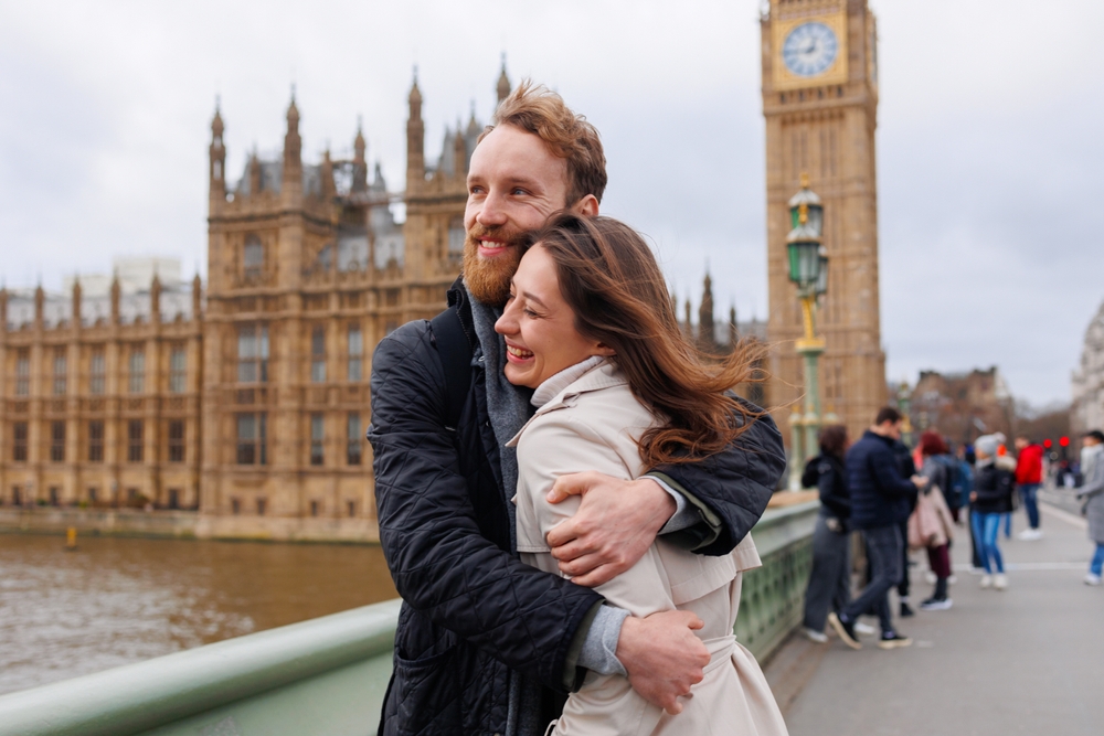 A couple hugging and smiling in front of Big Ben in London.