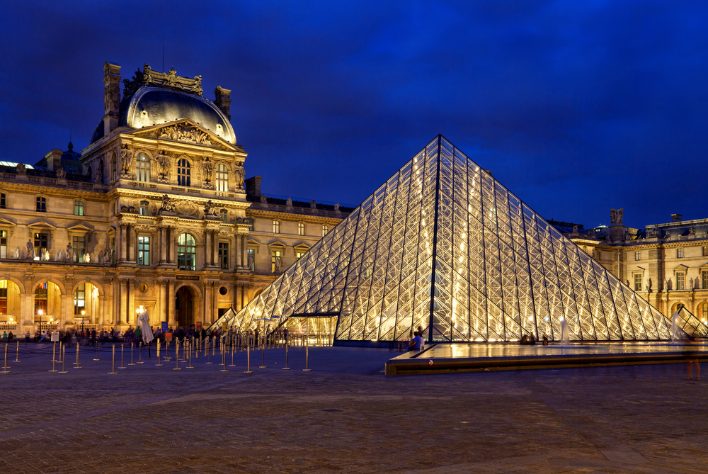 Night over the lit up glass pyramid at the Louvre.