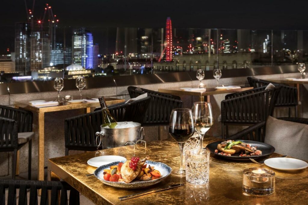 A dinner sitting on a table on one of the best rooftop bars in London at night.