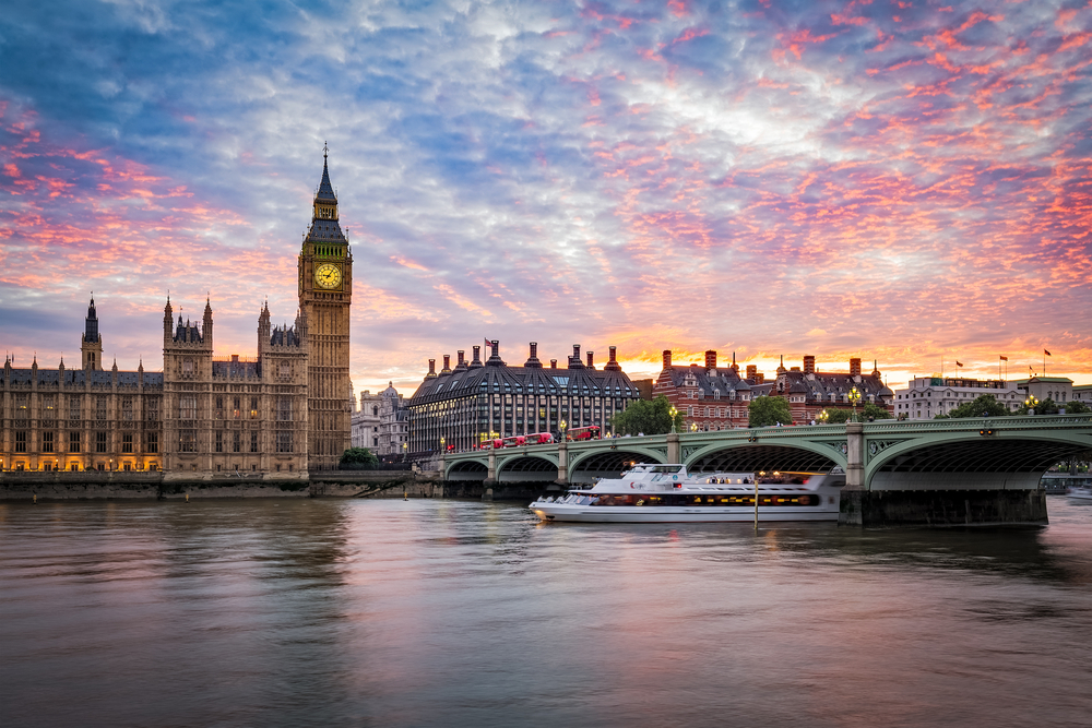 Sunset over the Thames River with a cruise ship and Big Ben.