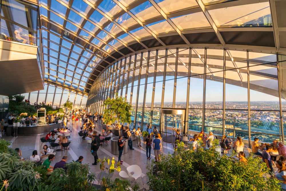 The Sky Garden with plants and glass walls and ceilings looking out at London.