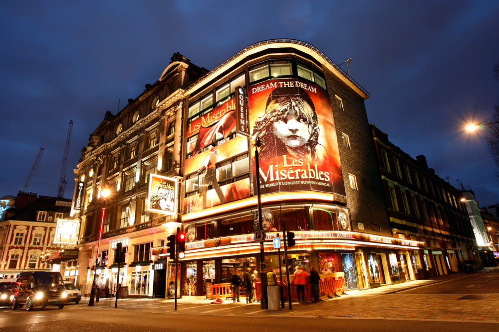 The Sondheim Theatre lit up at night with a poster for Les Misérables, one of the best things to do in London for couples.