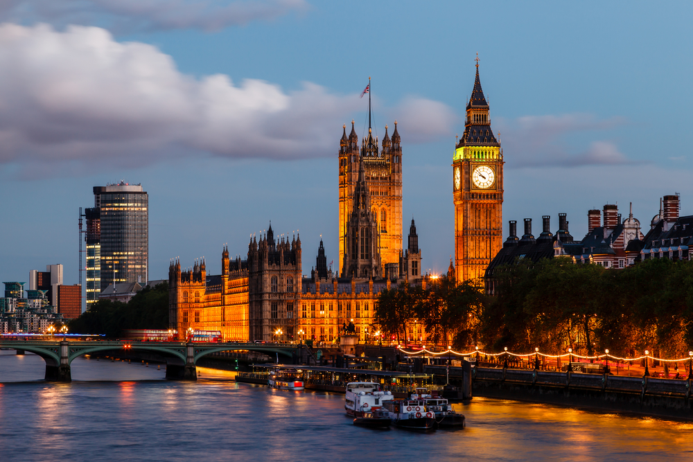 Big Ben and Parliament lit up at dusk next to the River Thames.