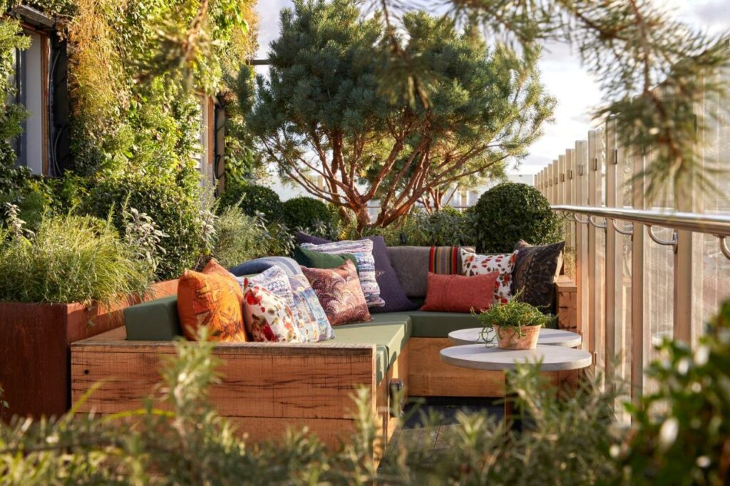 Couch with lots of pillows on a rooftop garden bar in London.