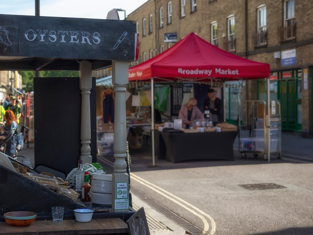 Stalls at Broadway Market with sign in an article about the best markets in London 