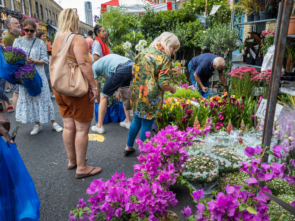 Columbia Road flower market with a crowd of visitors and tourists and traders busy selling their plants and flowers to customers. One of the best markets in London. 