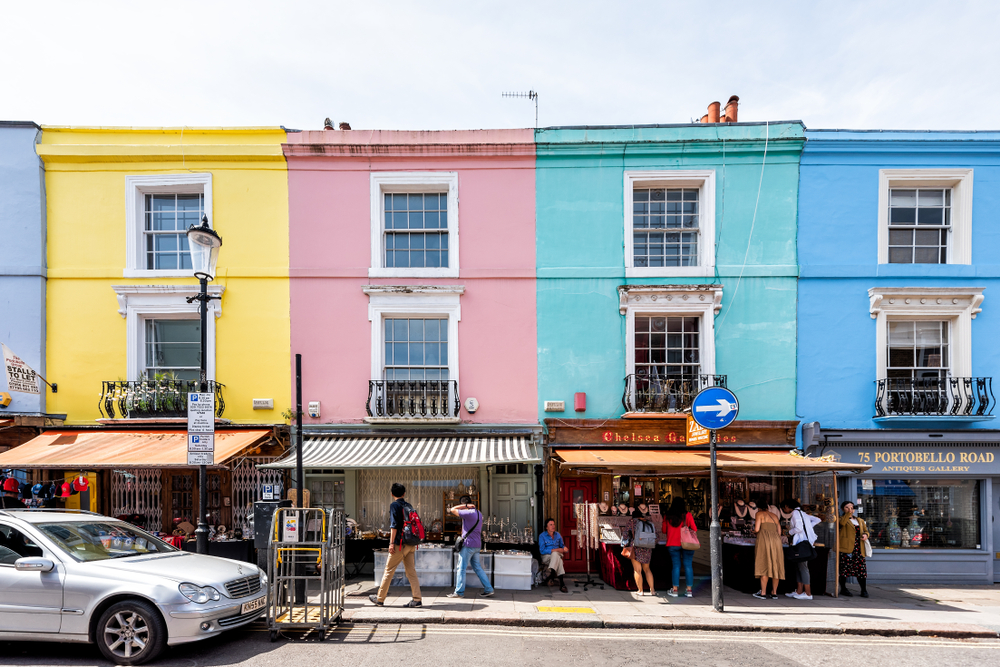 Colorful multicolored famous Notting Hill houses, road, people shopping in iconic center, Portobello market