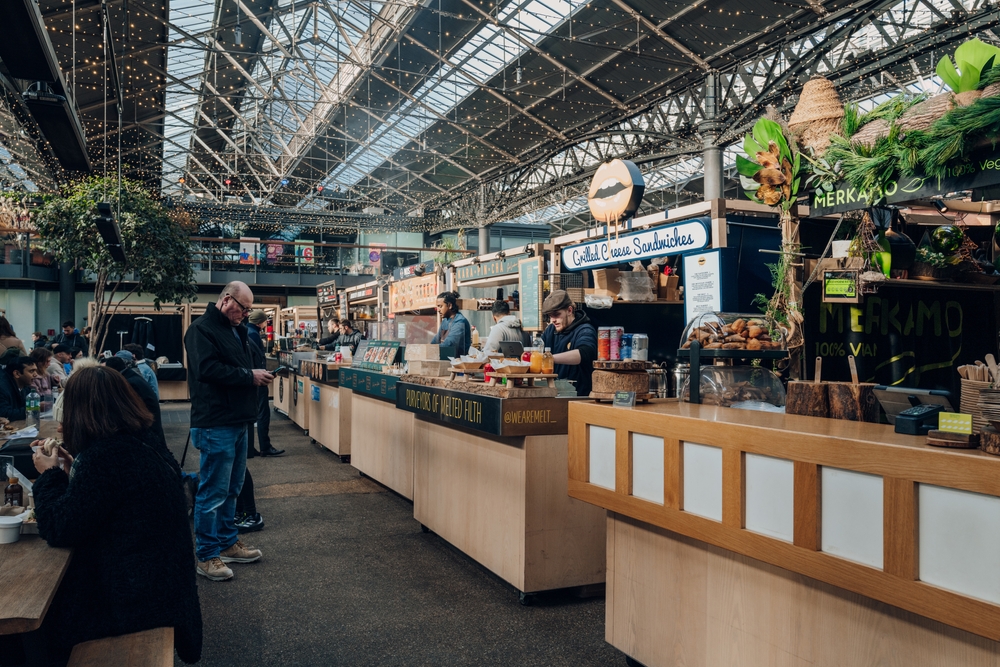 Row of food market stalls inside Spitalfields Market, one of the finest Victorian Markets in London with stalls offering fashion and food.