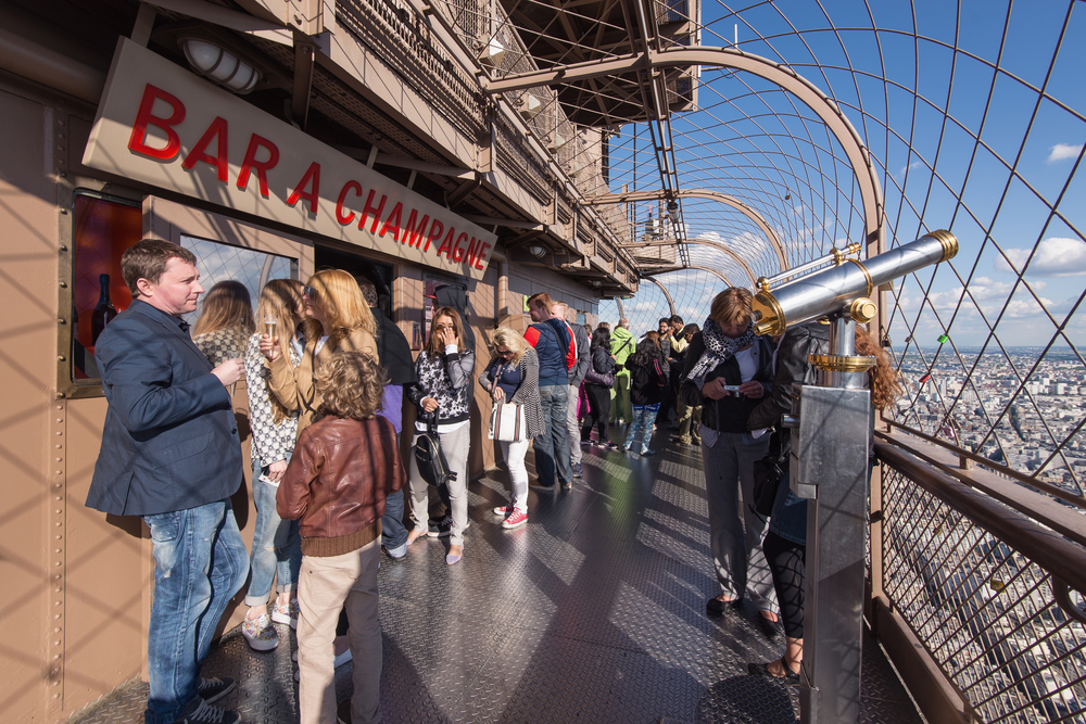 Tourists at the top of Eiffel Tower at Bar Champagne. with sweeping views of Paris.