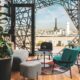 teal chairs around gray table with Eiffel Tower in background at rooftop bars in Paris