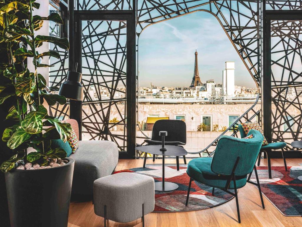 View of the Effiel tower from one of the rooftop bars in Paris. The bar has intricate metal work by the windows  and colourful furniture. 