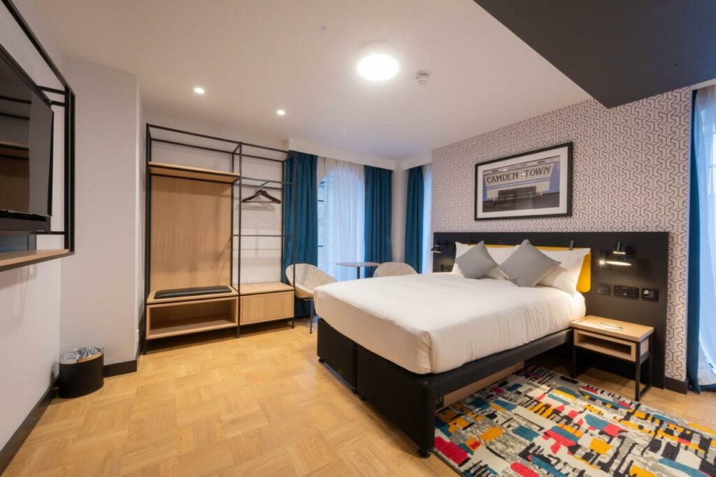 spacious room with camden town art, a bed with white bedding, and an open wardrobe