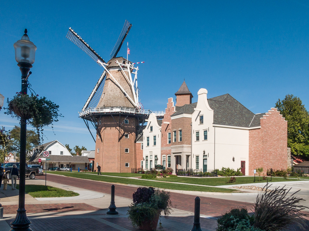 Tall, historic windmill next to Dutch styled buildings in Pella, Iowa, one of the best Midwest weekend getaways.