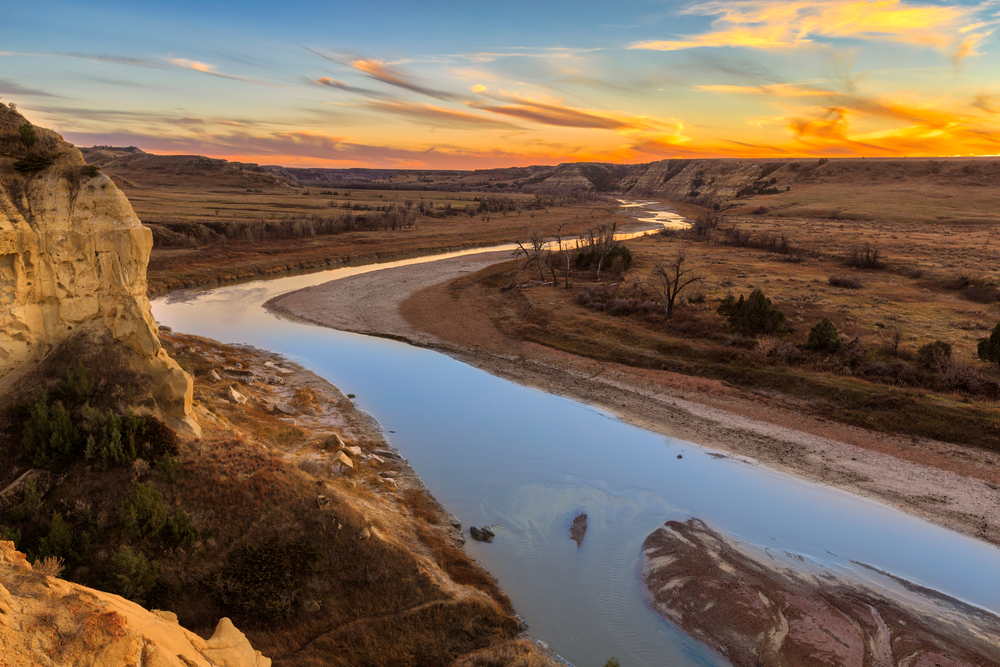 View looking out over Theodore Roosevelt National Park during an orange sunset.