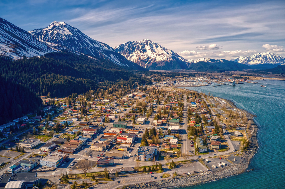 Aerial view of Seward set along the ocean at the bottom of snow-capped mountains.