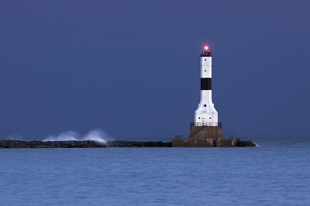 Tall, black and white lighthouse at night.