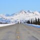 Plowed highway heading towards mountains in Alaska in winter.