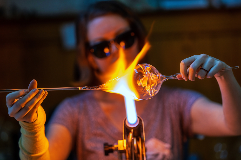 A person creating a piece of blown glass art