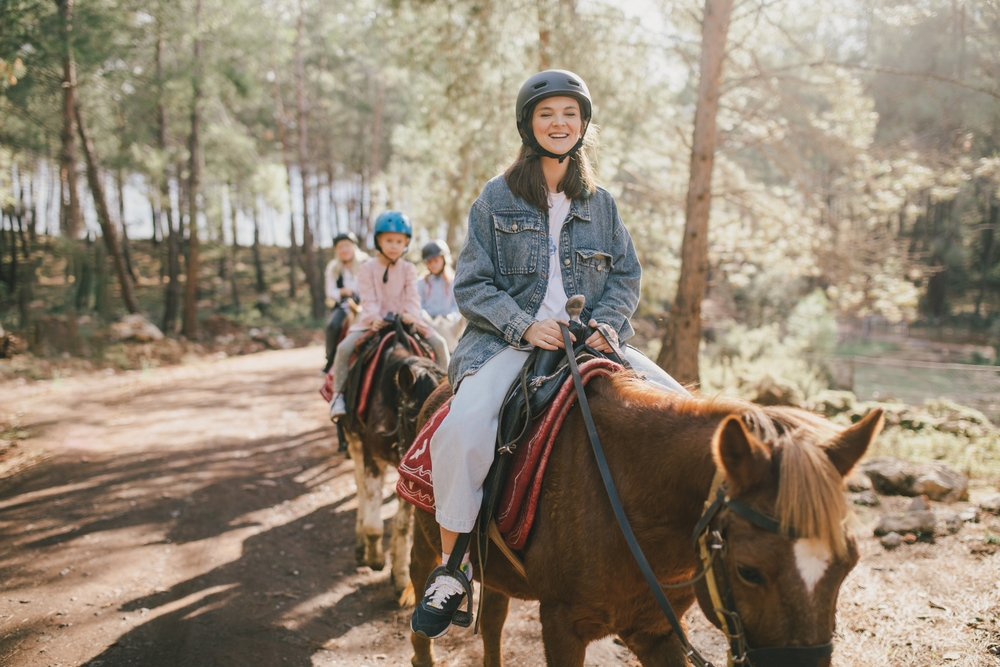A woman and young girls riding horses in the woods things to do in Hocking Hills