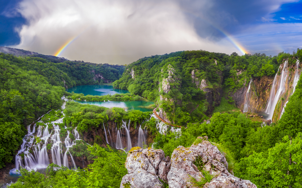 Panoramic view of lakes, waterfalls, and a rainbow at Plitvice Lakes National Park, one of the best day trips from Dubrovnik.