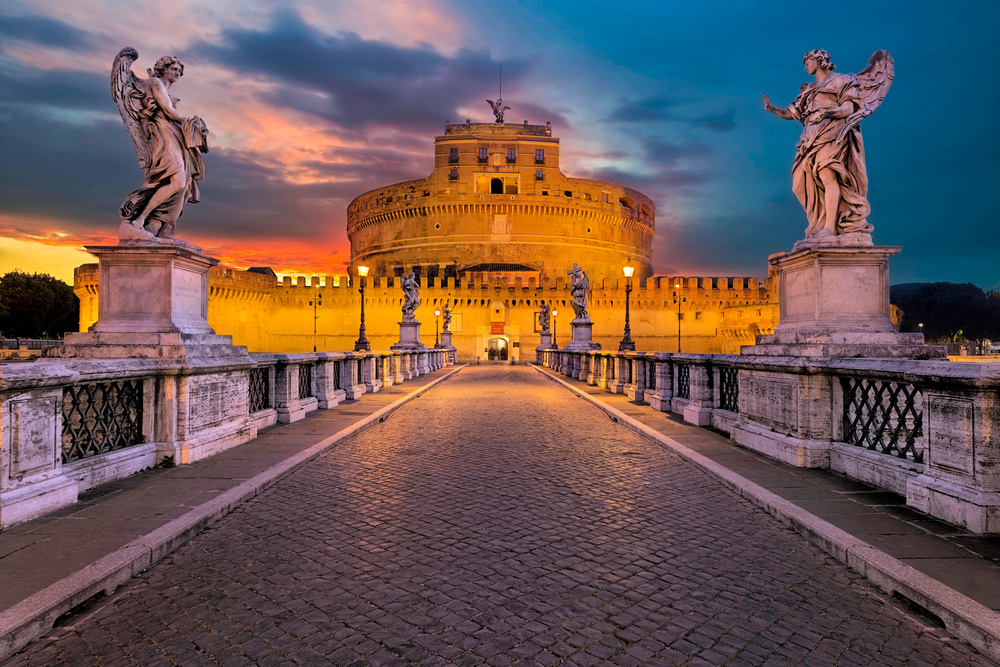 Vivid sunset over a bridge leading to Castel Sant'Angelo with statues of angels.