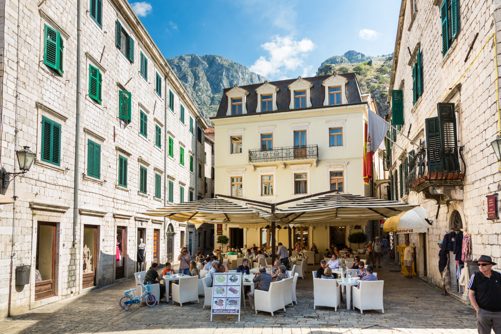 people dining under umbrellas outside of a restaurant in Kotor.