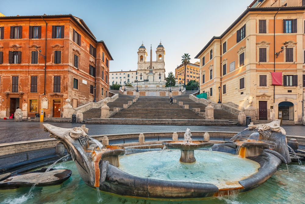 Early morning over the Spanish Steps with a fountain at the bottom and a church at the top.