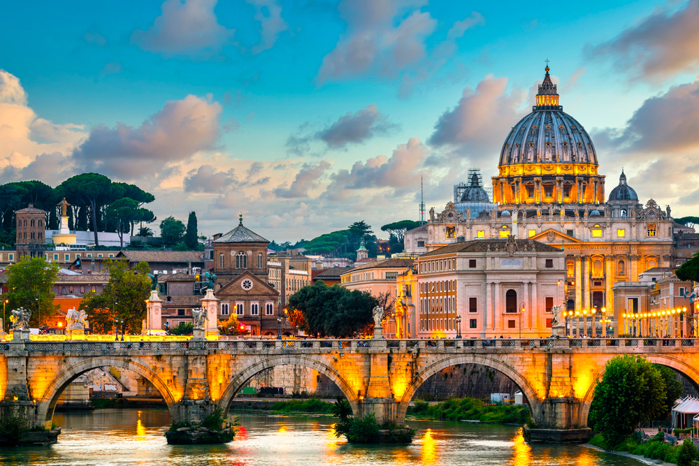 View of St.Peter's Basilica and Ponte Vittorio Emanuele II bridge lit up at dusk.