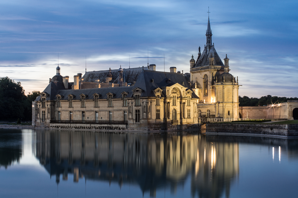 Castle of Chantilly at dusk the castle is reflected in the water. 
