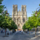 Gothic cathedral in background with symmetrical trees lining path in foreground, day trips from Paris by train