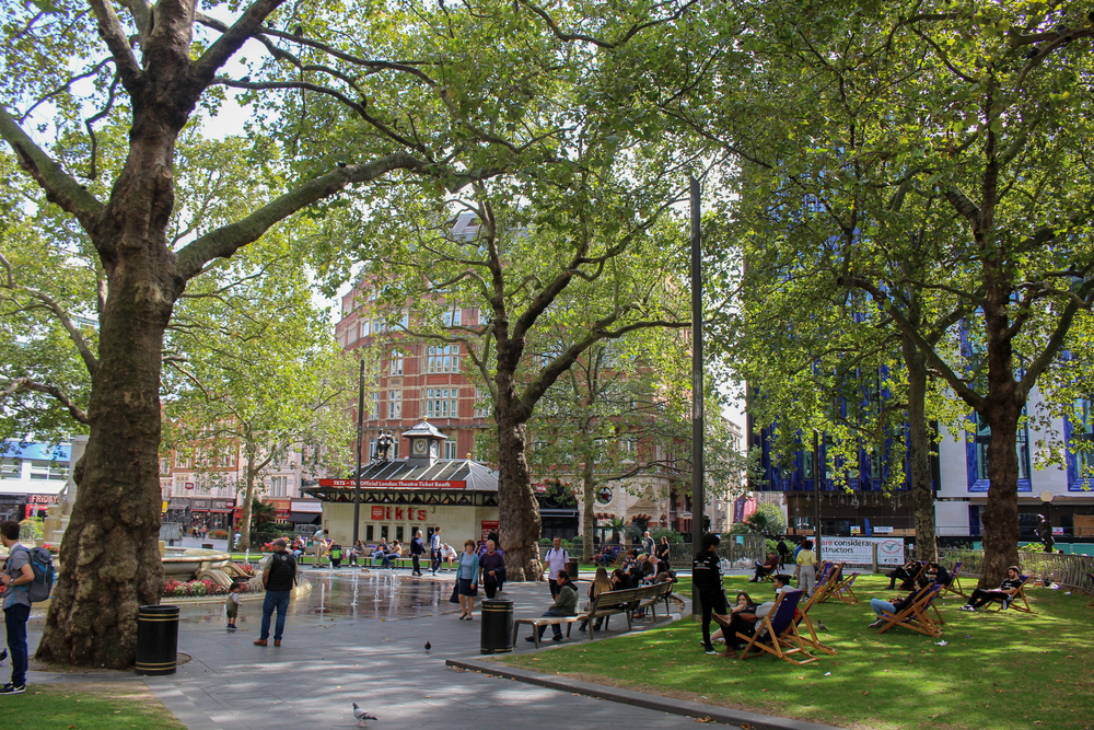 People relaxing in Leicester Square, central London one of the places to go on one day to London. 