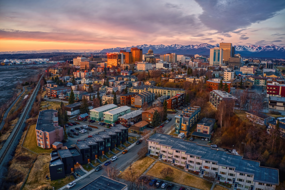Aerial view of a vivid sunset over downtown Anchorage with snow-capped mountains in the distance.