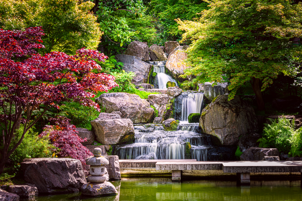 Beautiful Kyoto Gardens with a tiered waterfall among stones and lots of greenery.