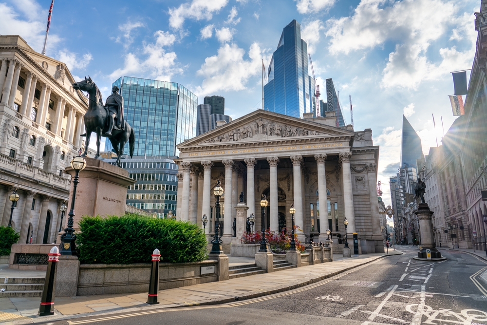 The columned Royal Exchange building with a horse and rider statue in front and the modem skyline beyond it.