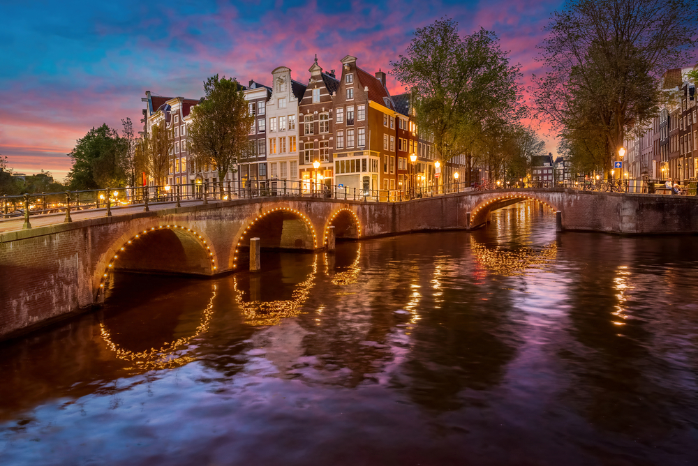 Vivid sunset over canals and lit up bridges in the shopping district of Amsterdam.