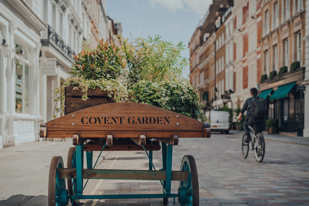 'Covent Garden" area name sign on a wooden cart with flowers on a street in Covent Garden. A great place to stay on your first time in London. 