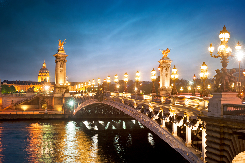 Dusk over the Alexandre III Bridge with lit up ornate lampposts.