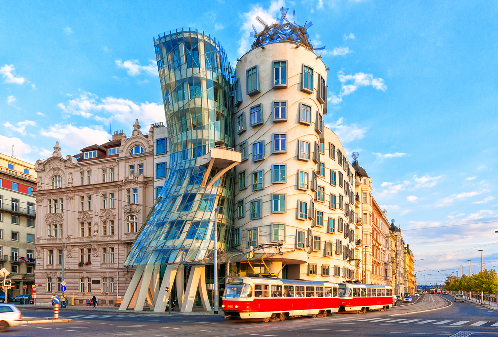 Famous Dancing House glass building with a tram going in front of it on a sunny day in Prague.
